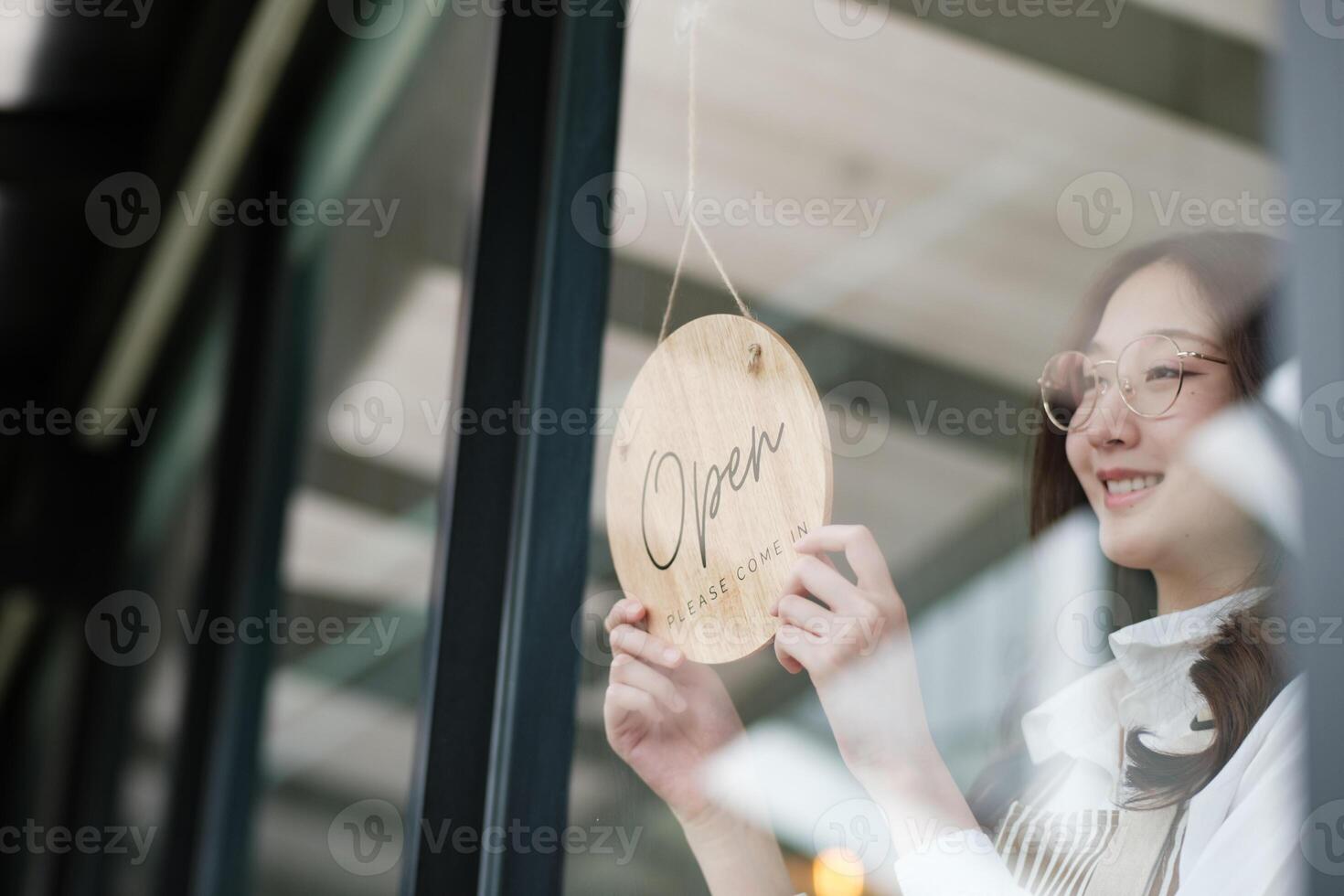 Shopkeeper flipping an open sign at the storefront, signaling the start of the business day. photo