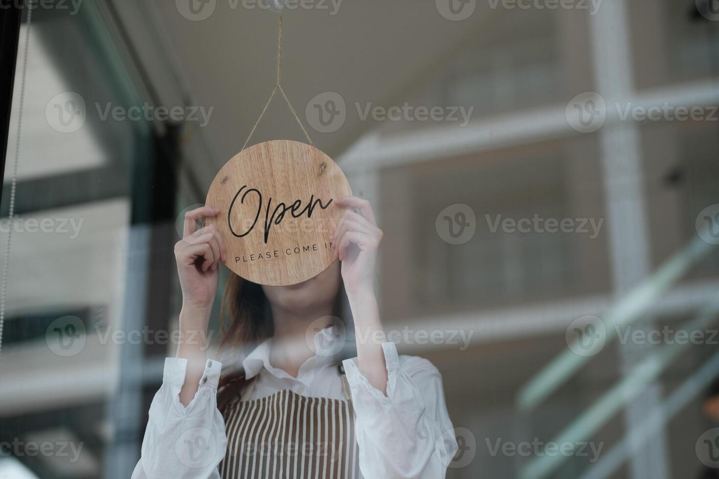 Shopkeeper flipping an open sign at the storefront, signaling the start of the business day. photo
