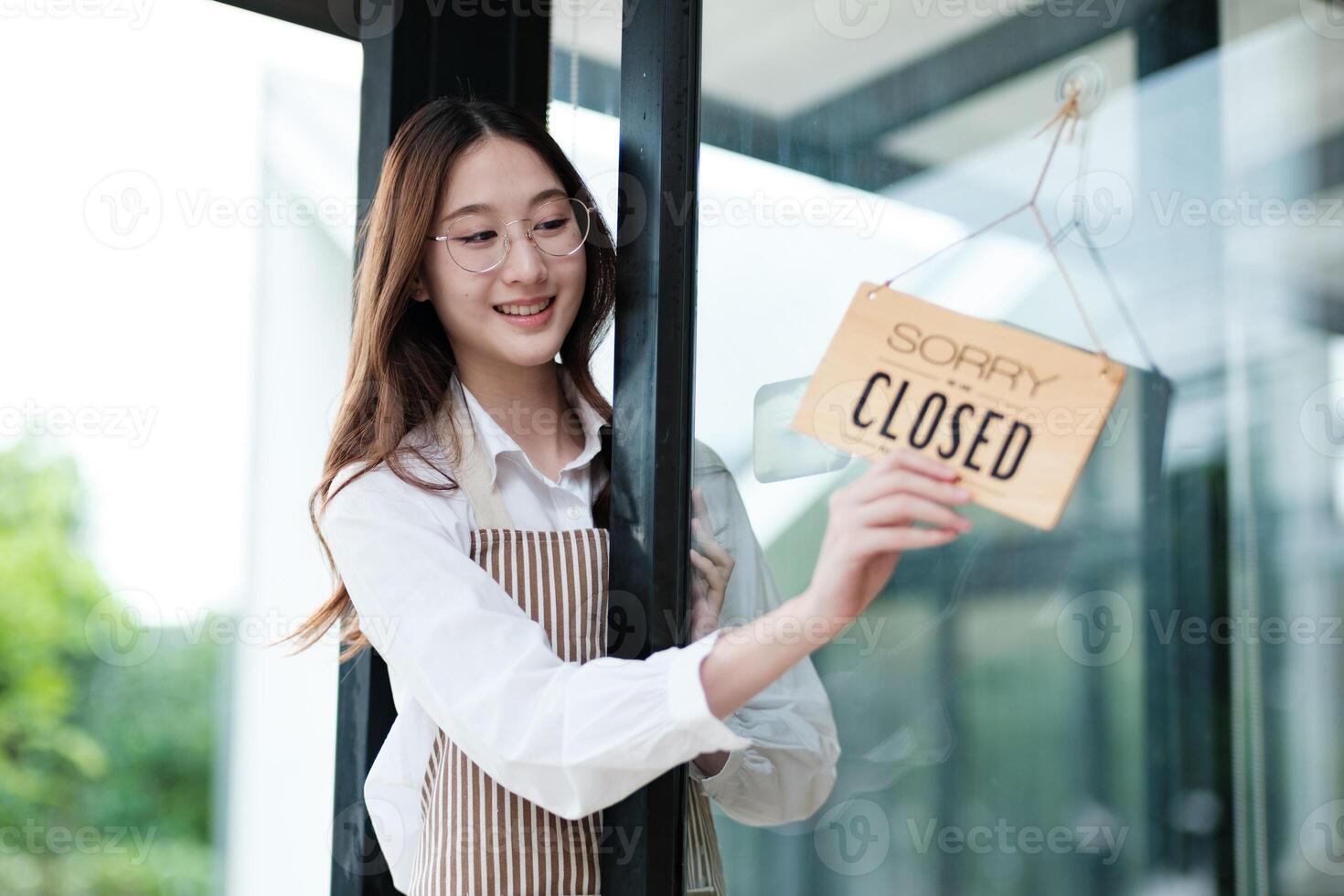 Shopkeeper flipping an open sign at the storefront, signaling the start of the business day. photo