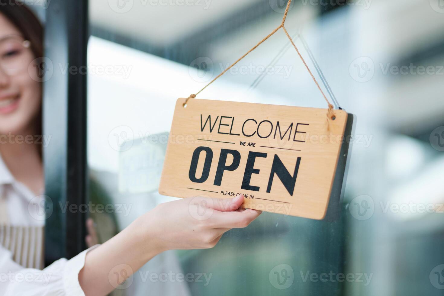 Shopkeeper flipping an open sign at the storefront, signaling the start of the business day. photo