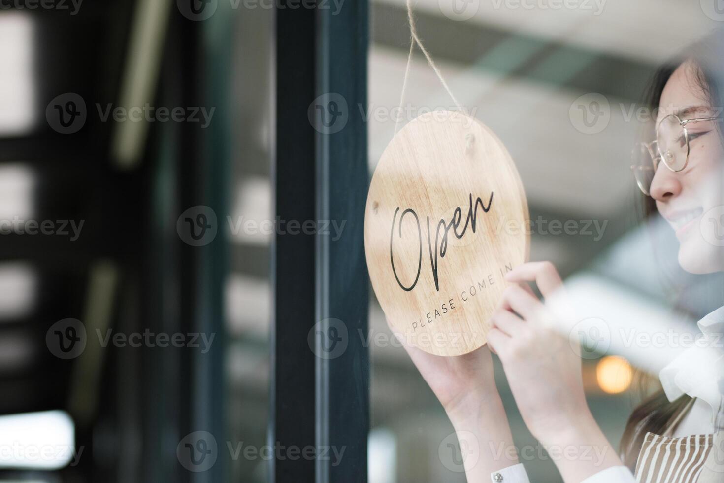 Shopkeeper flipping an open sign at the storefront, signaling the start of the business day. photo