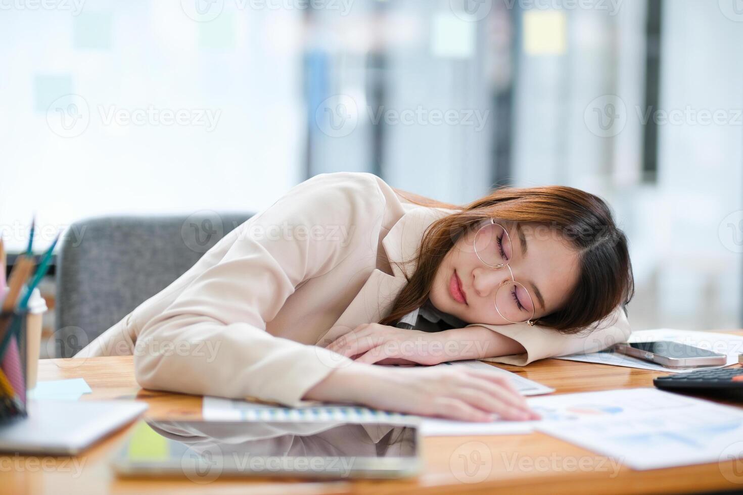Exhausted businesswoman sleeping on her desk during a busy workday in a modern office photo