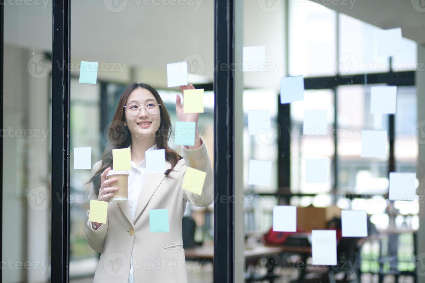 Businesswoman writing on sticky notes while planning business strategy photo