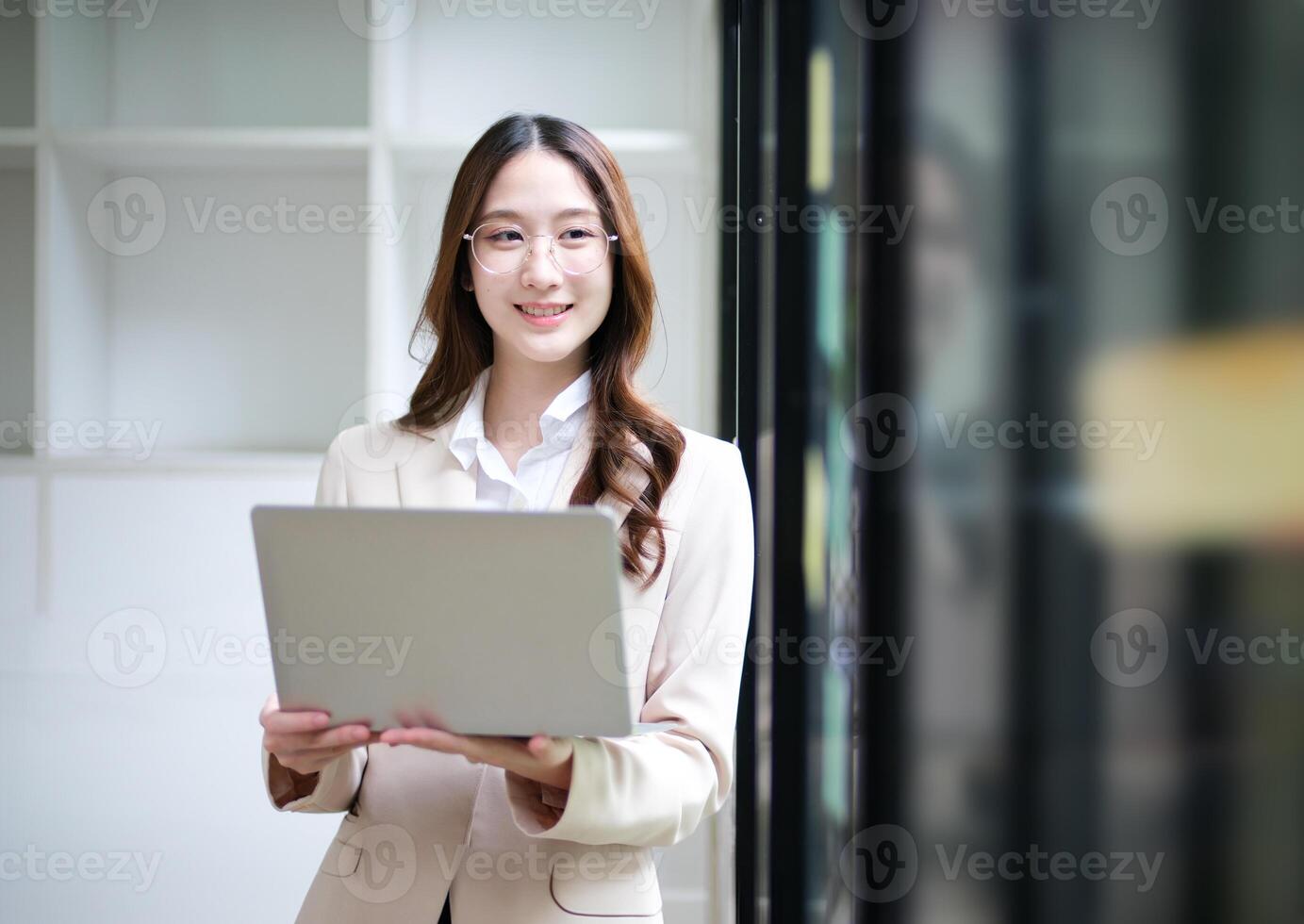 Businesswoman using a laptop and reviewing data with sticky notes in the background. photo