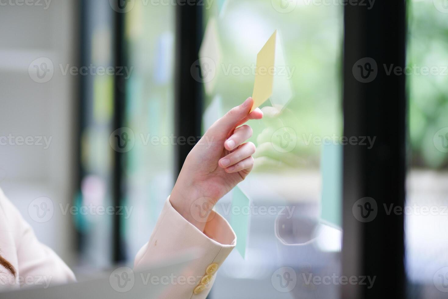 Close up of a businesswoman hand placing sticky notes on a glass board photo