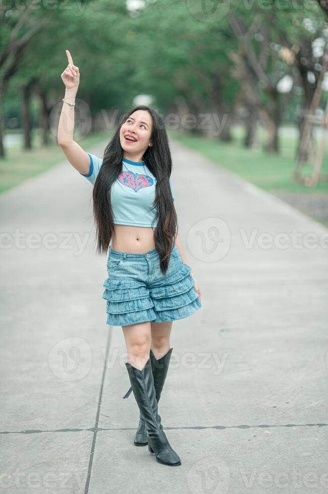 A woman in a blue shirt and short skirt is pointing photo