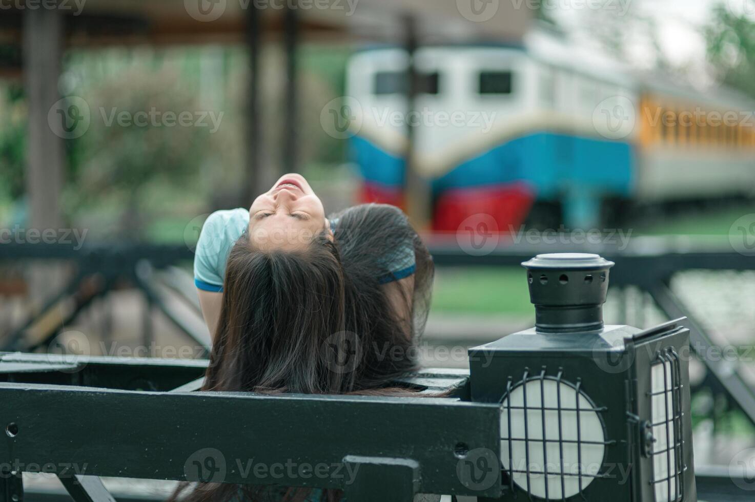 A woman is sitting on a bench with her head up photo