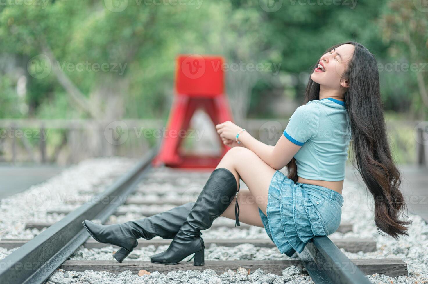 A woman in boots sitting on railroad tracks photo