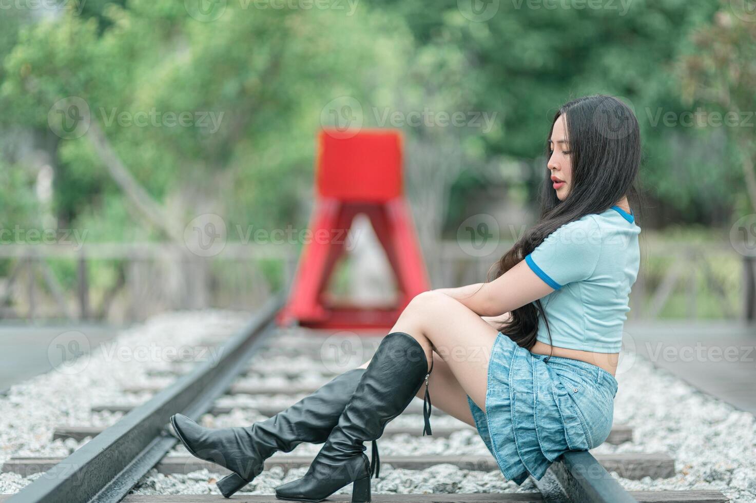 A woman in boots sitting on railroad tracks photo