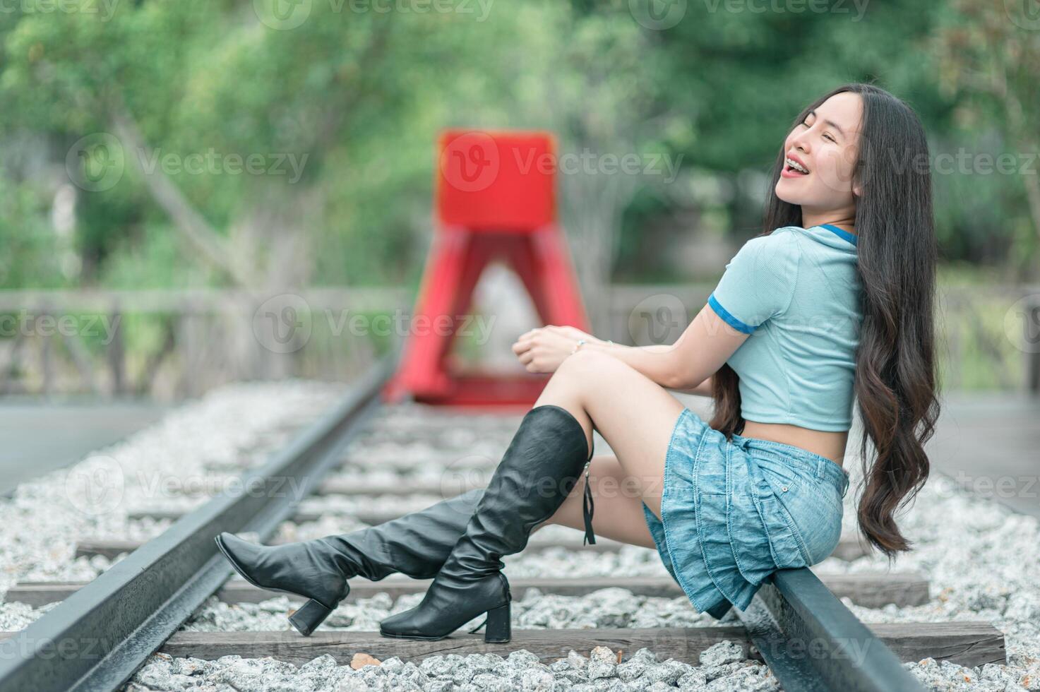 A woman in boots sitting on the railroad tracks photo