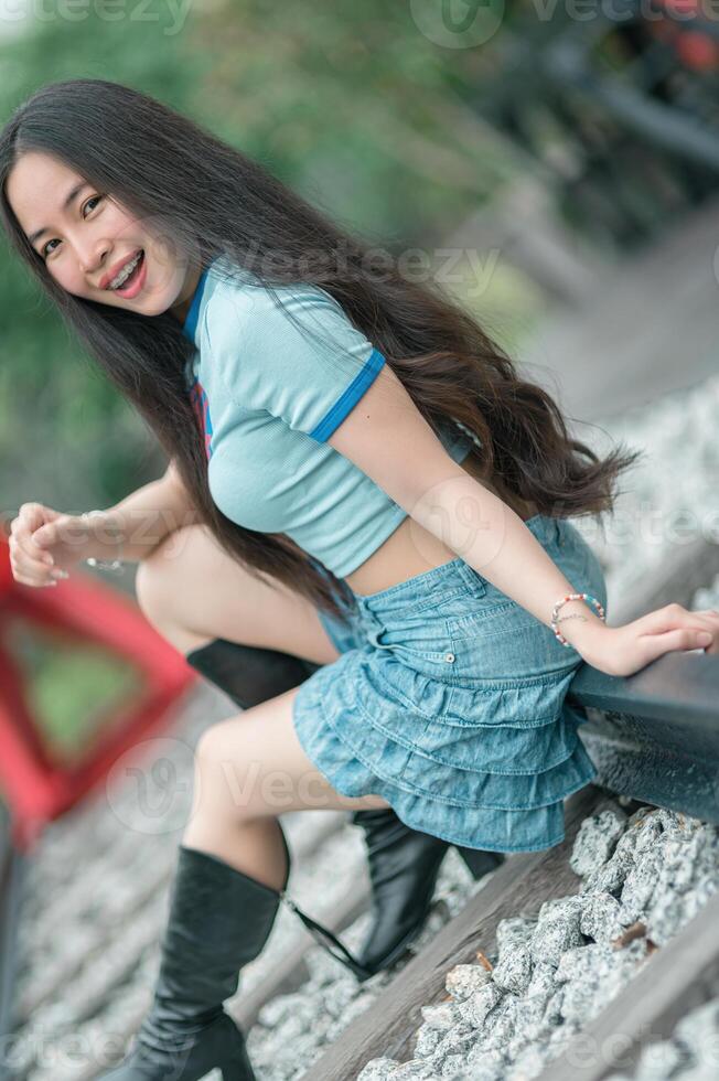 A woman in a blue shirt and skirt sitting on a railroad track photo