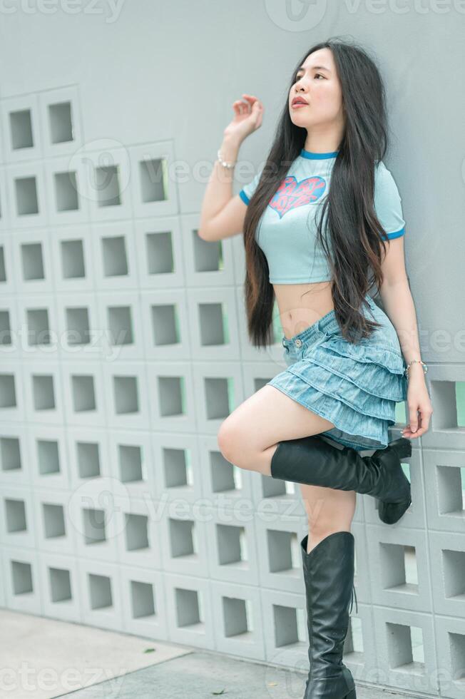 A woman in a blue shirt and black boots posing photo