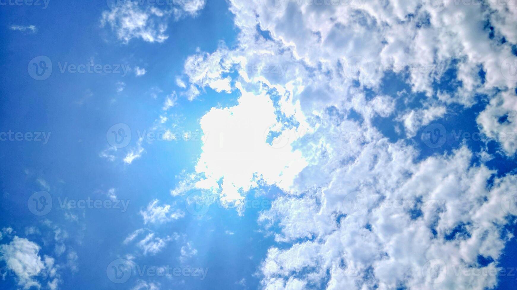 The sun shines through the clouds in a blue sky photo