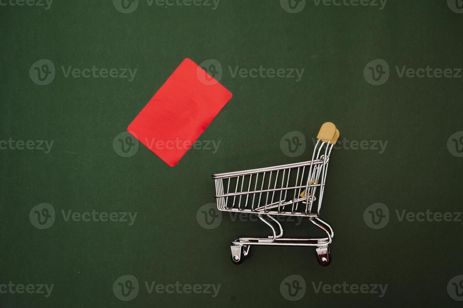 a mini grocery cart and a red credit card on a green background. photo