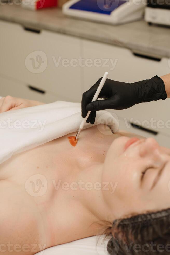 The cosmetologist applies a liquid gel to the face with a wide brush, the carboxytherapy procedure and its preparations. photo