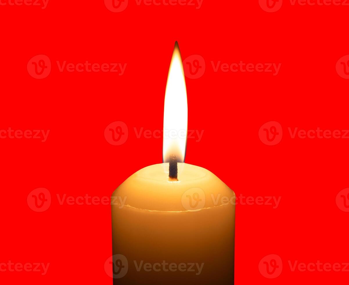 A single burning candle flame or light glowing on a big white candle isolated on red background with clipping path photo