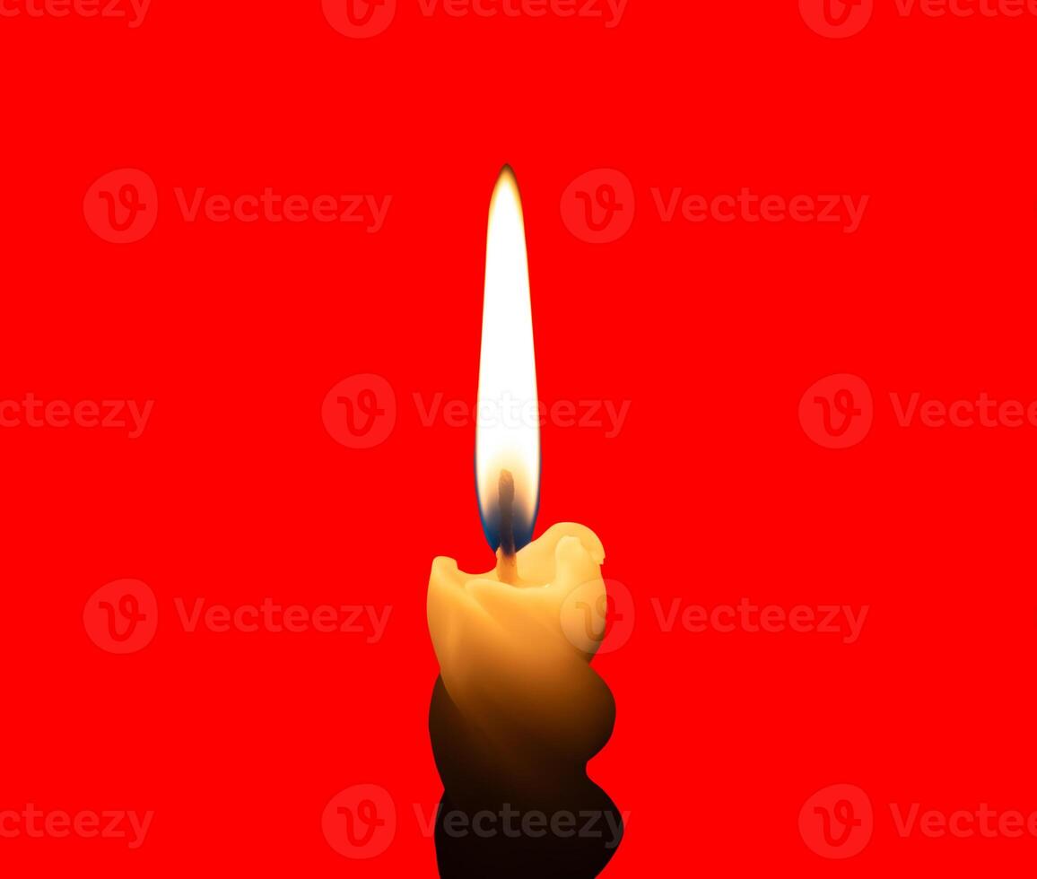 A single burning candle flame or light glowing on a small spiral yellow candle isolated on red background with clipping path photo