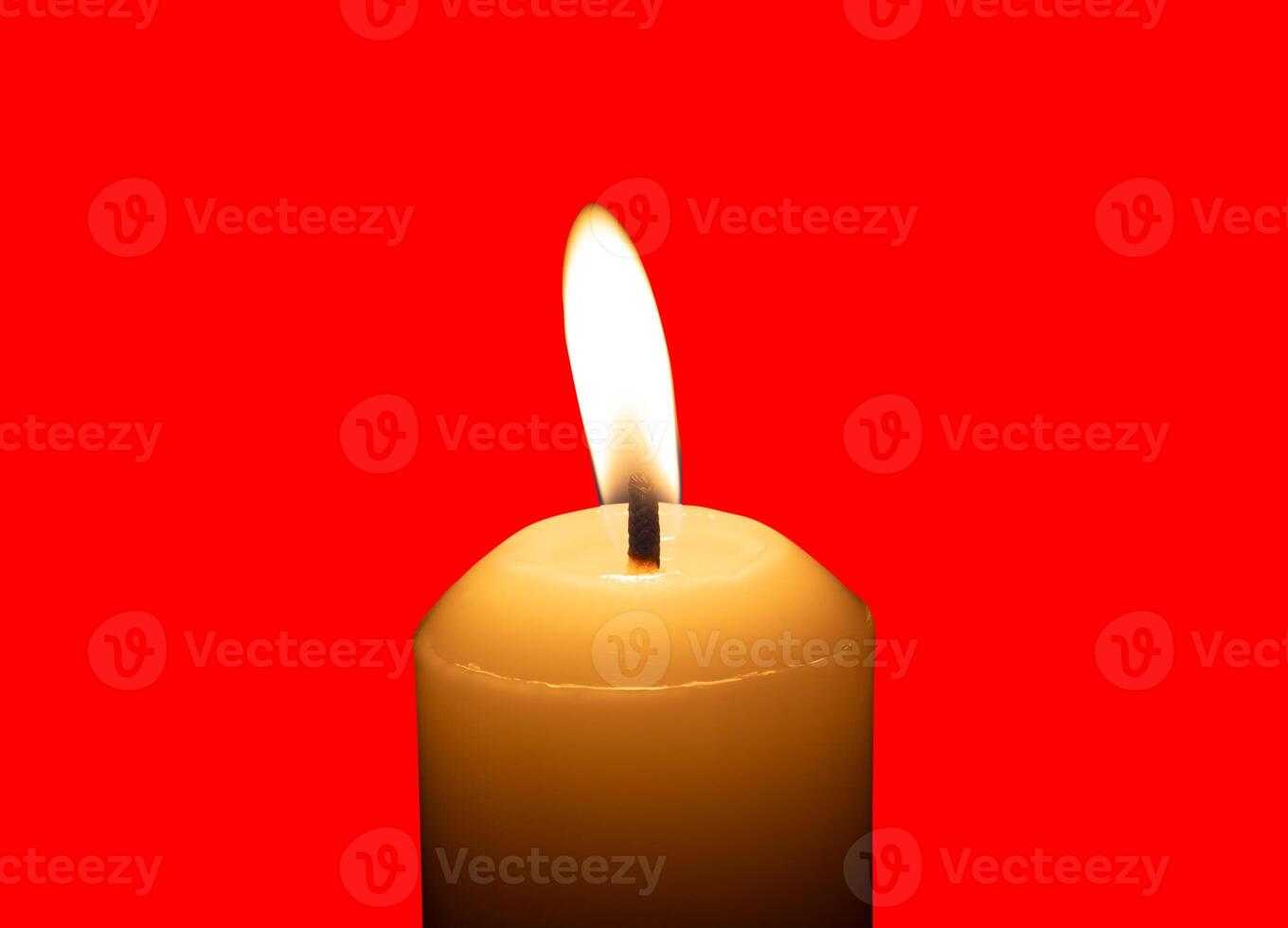 A single burning candle flame or light glowing on a big white candle isolated on red background with clipping path photo