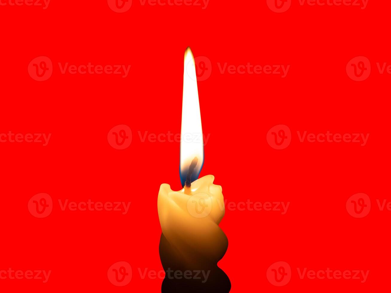 A single burning candle flame or light glowing on a small spiral yellow candle isolated on red background with clipping path photo
