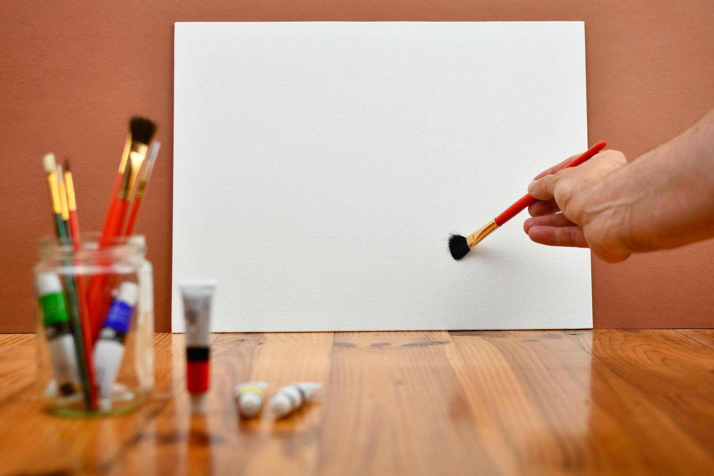 A person holding a paintbrush and a white piece of paper photo