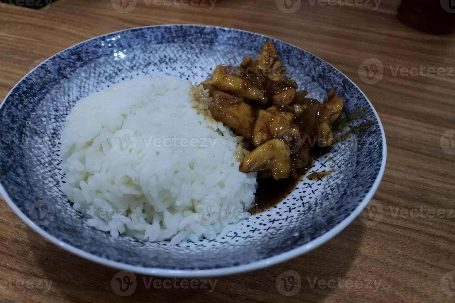 Ayam bakar Penyet is a fried chicken served with hot chili in a plate with fresh vegetables, slices of cucumber and basil leaves photo
