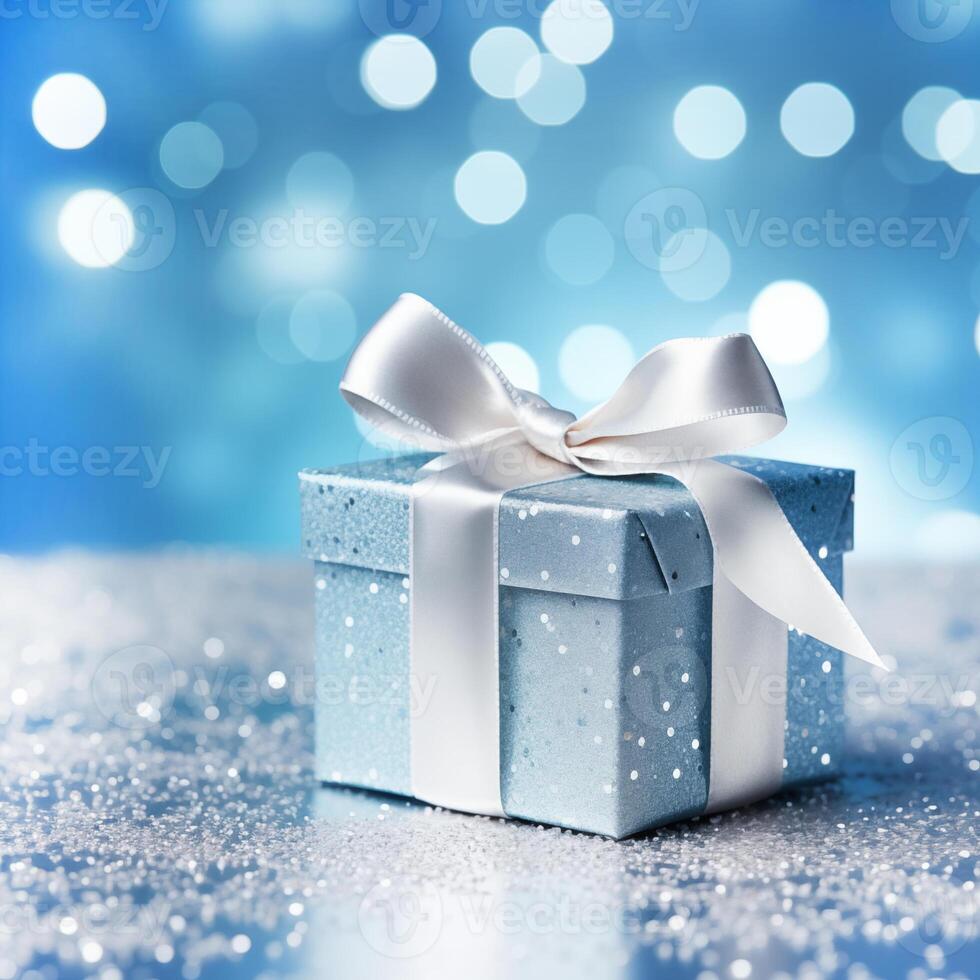 close up of a blue box with glitter packaging wrapped in white ribbon on a surface with silver confetti on a blue background with white bokeh photo