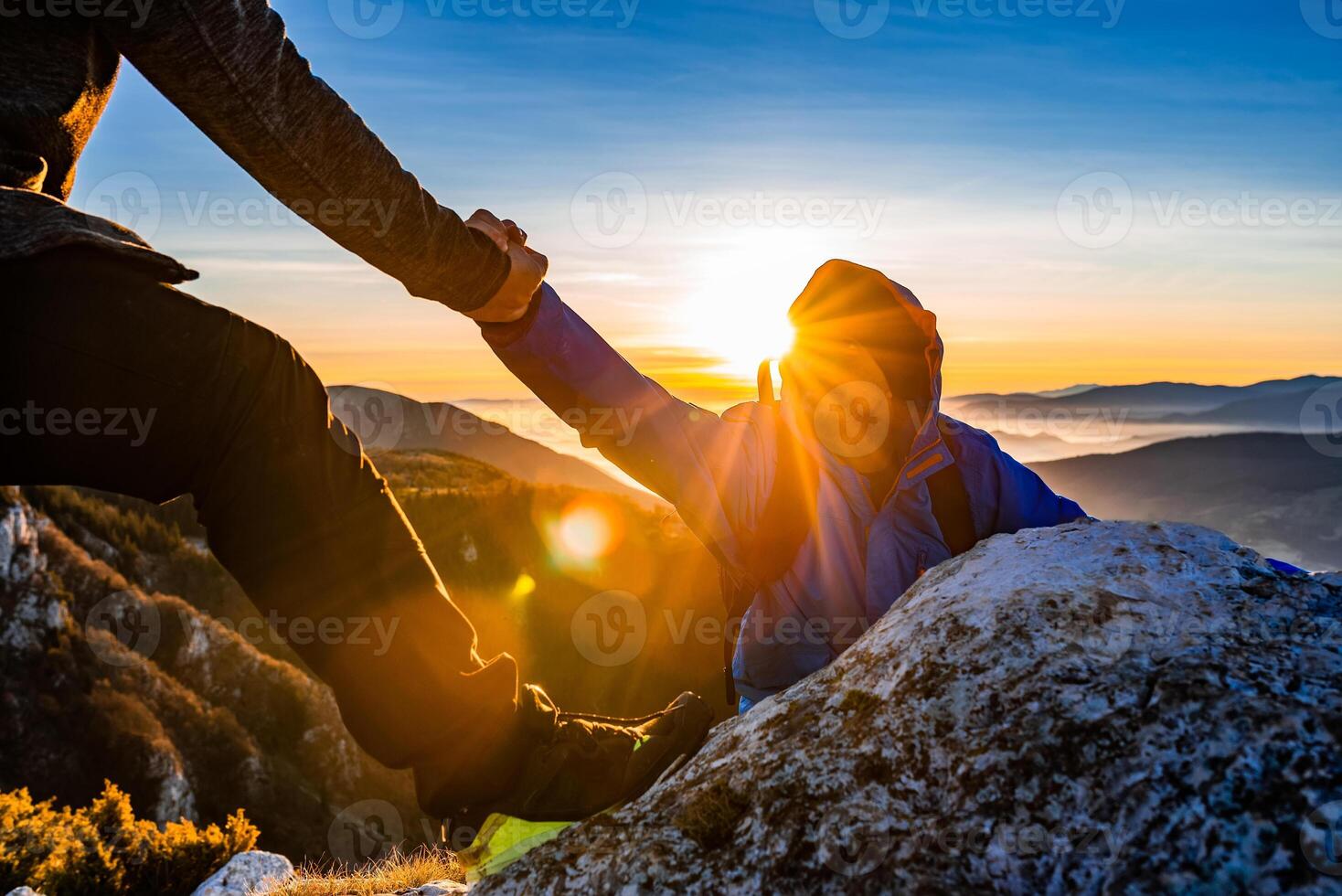 Hiking team people helping each other friend giving a helping hand while climbing up on the mountain rock adventure travel concept of support trust teamwork success. photo