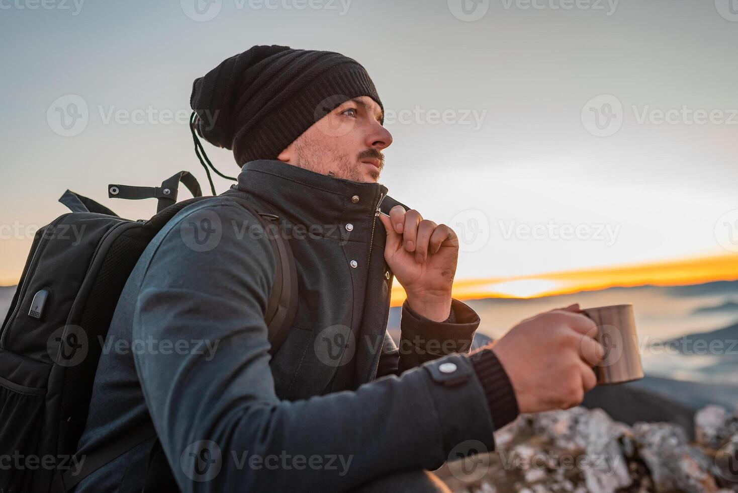 A male traveler drinking a cup of coffee during the hiking on the mountain. photo