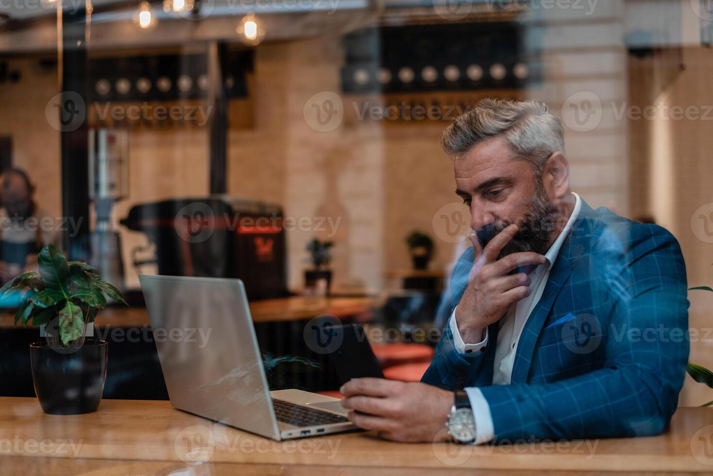 A thoughtful worried mature business man thinking of problem solution while working on a laptop in the office near the window. photo