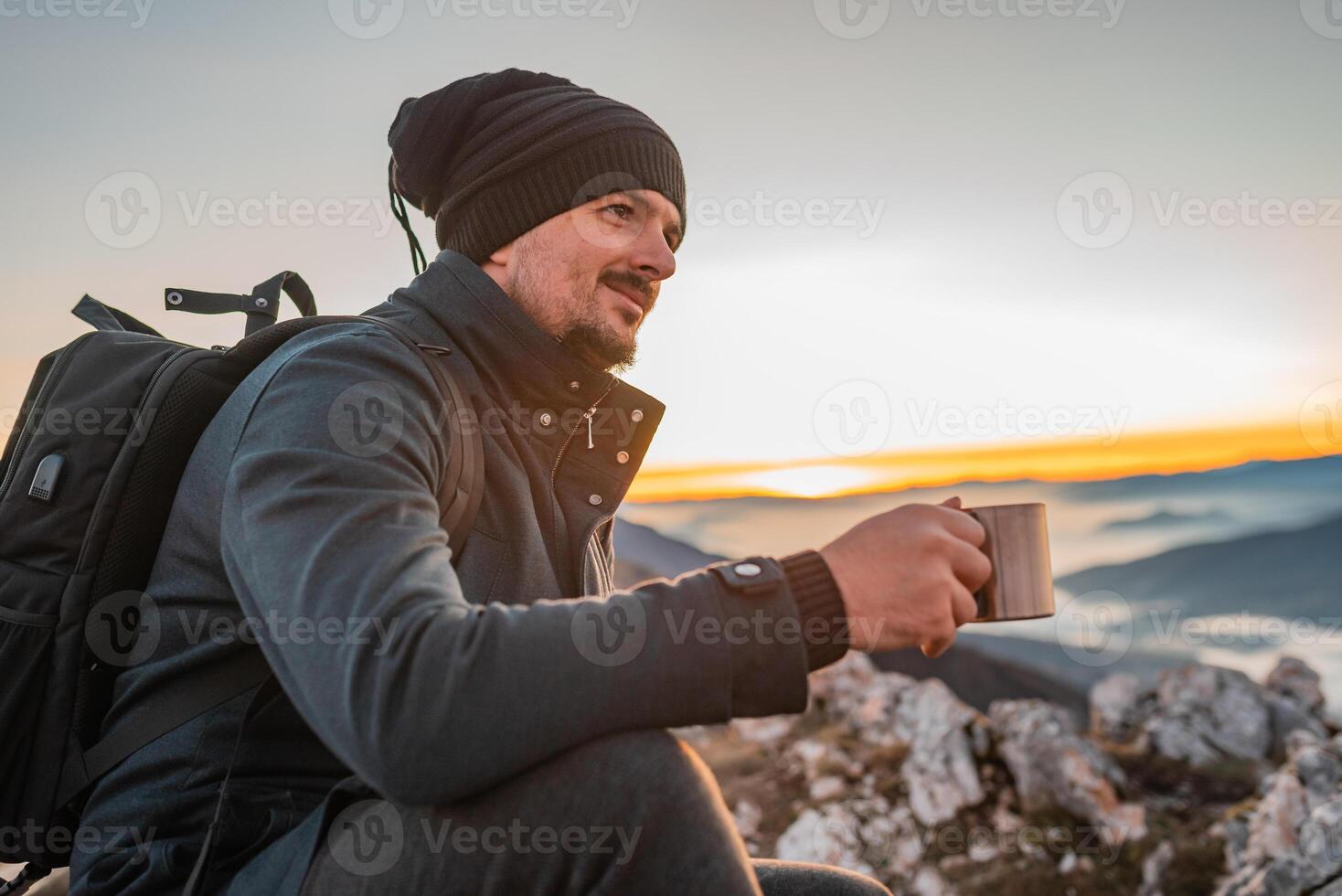 A happy man traveler drinking a cup of coffee during the hiking on the mountain. photo