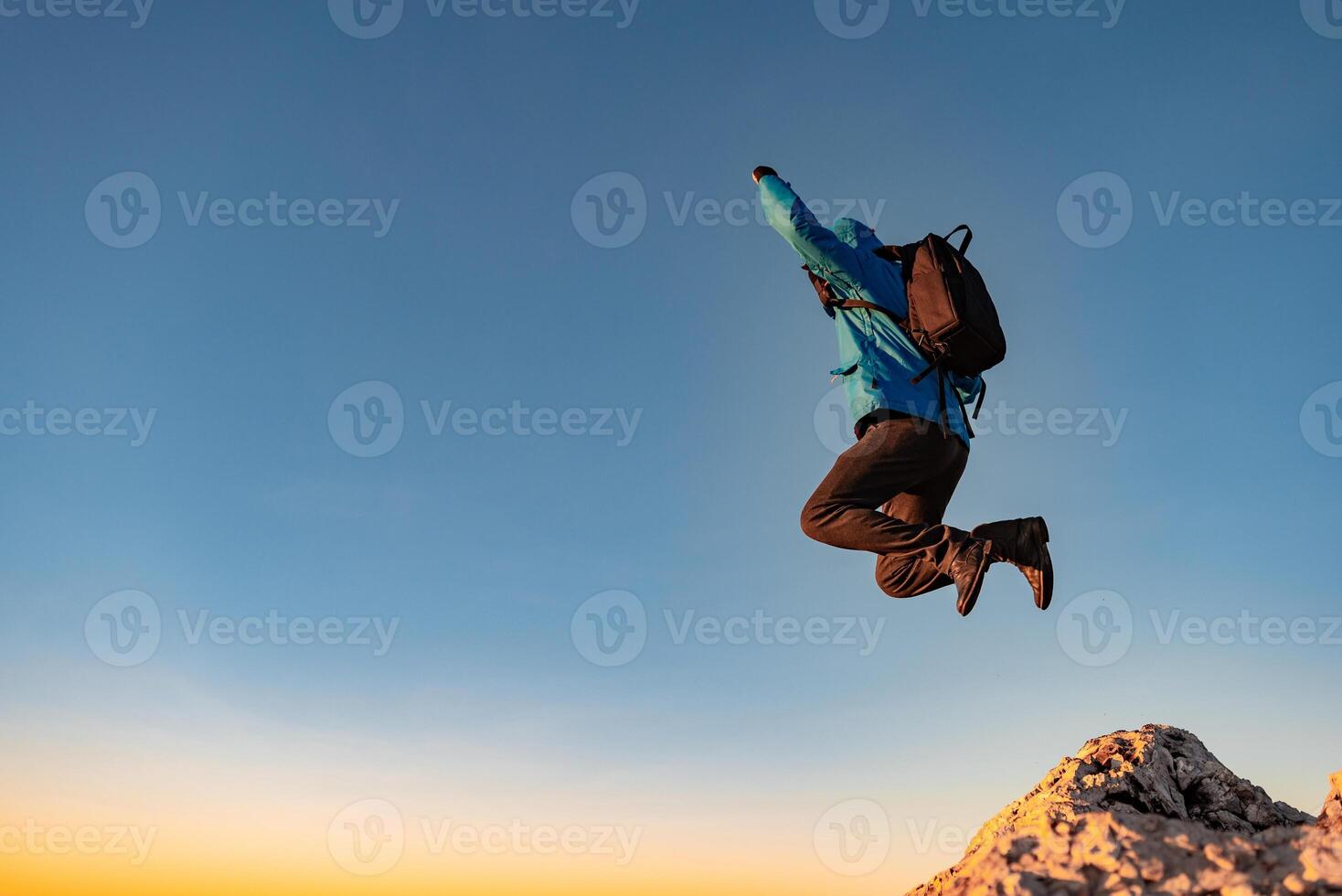 A happy man jumping on top of a mountain concept of adventure travel extreme sport hiking. photo