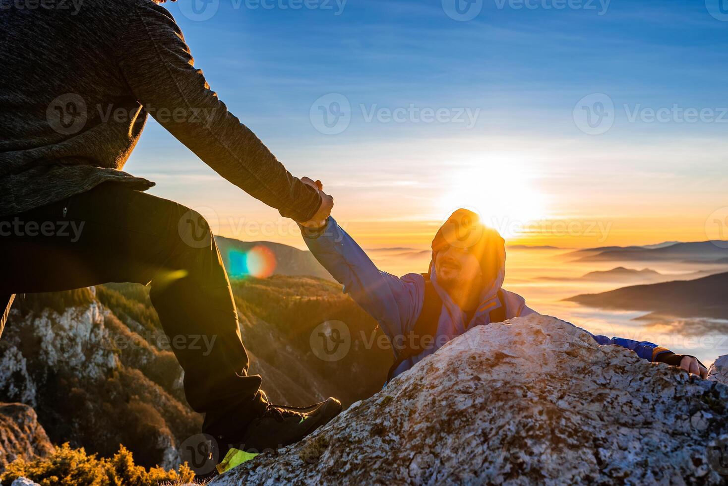Hiking team people helping each other friend giving a helping hand while climbing up on the mountain rock adventure travel concept of support trust teamwork success. photo