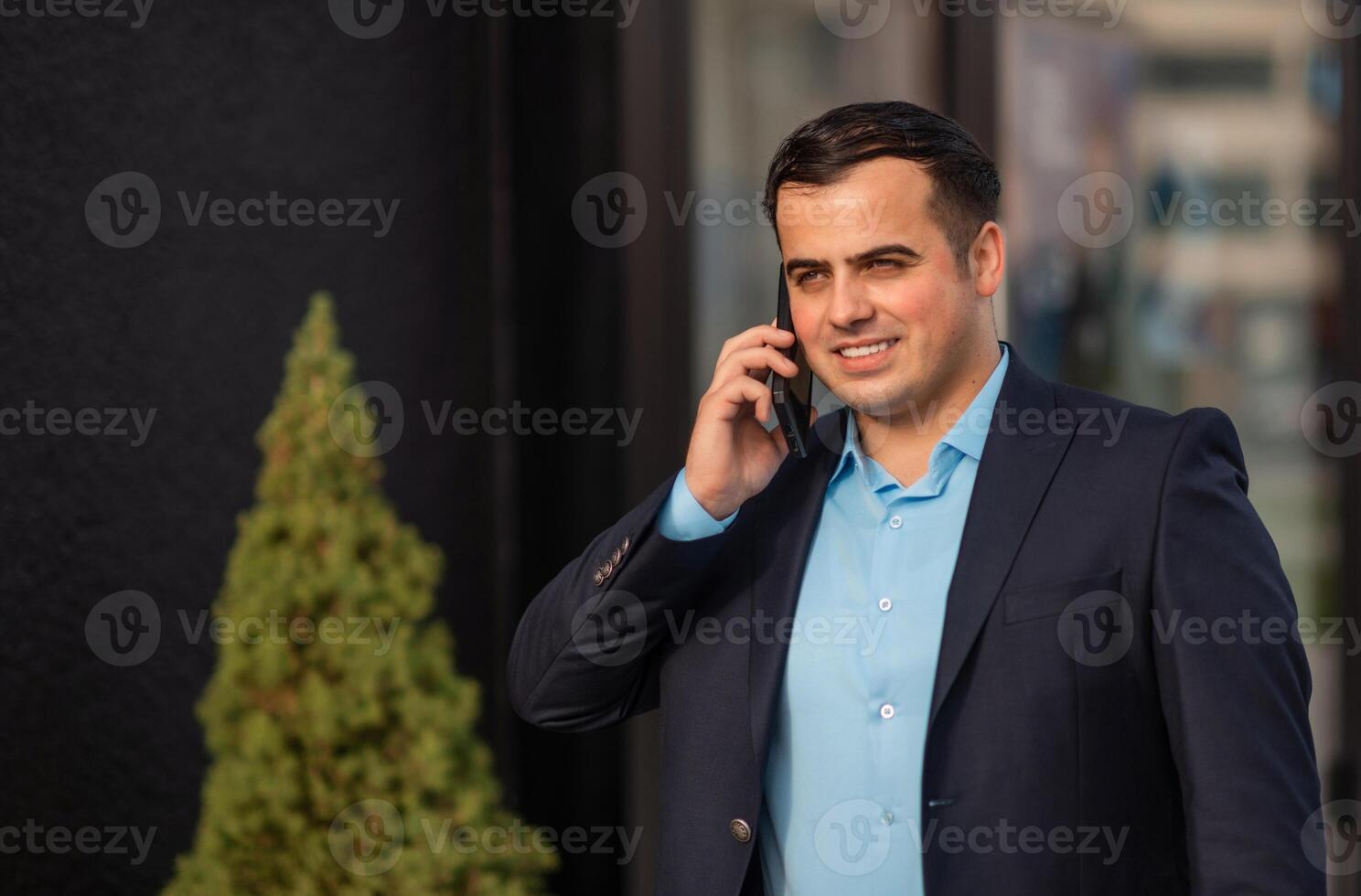 A happy young business man talking on his phone mobile outside near the office building. photo