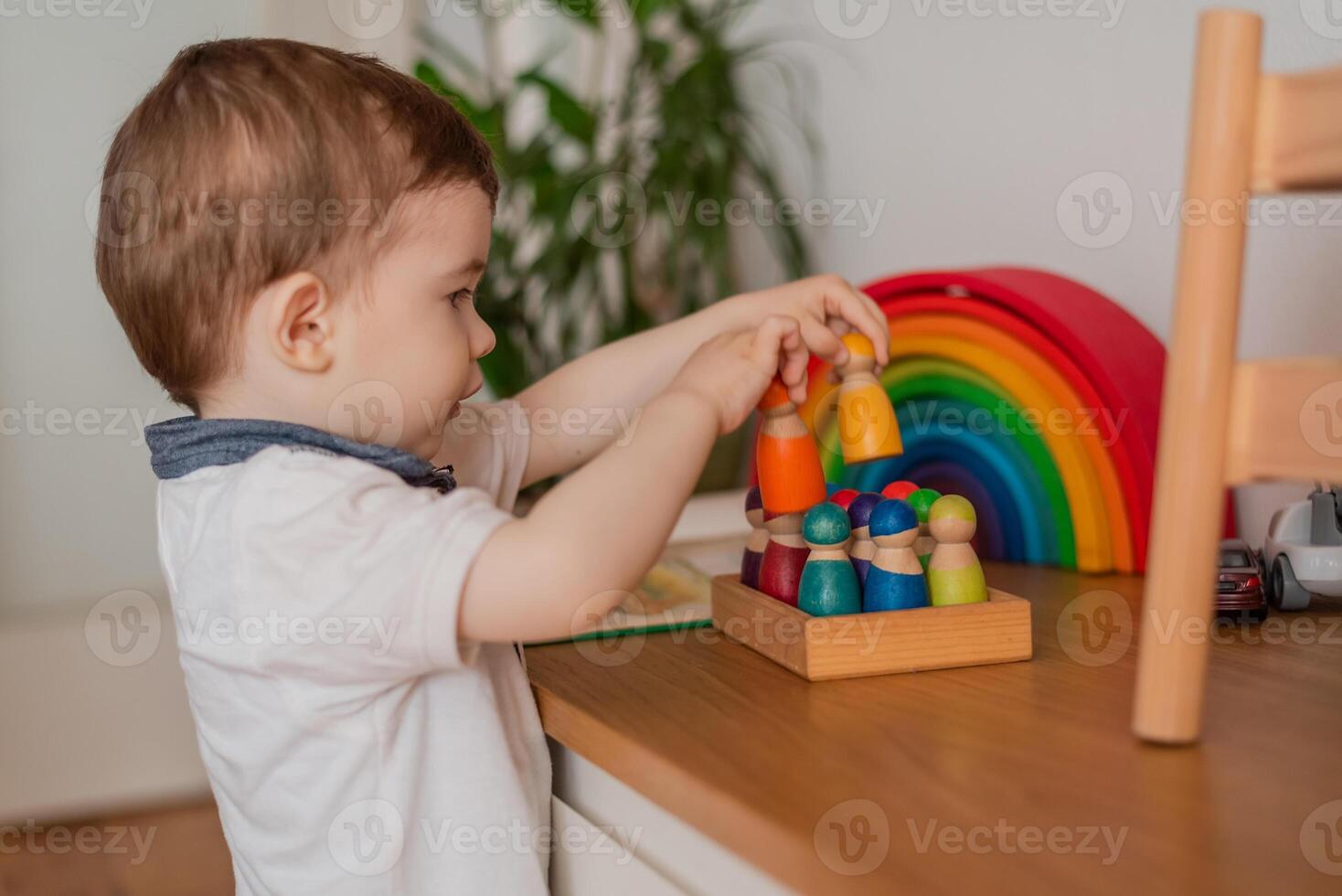 A Montessori child boy playful learning arranging by engaged colorful wooden sensorial blocks educational toys cognitive creative skills. photo