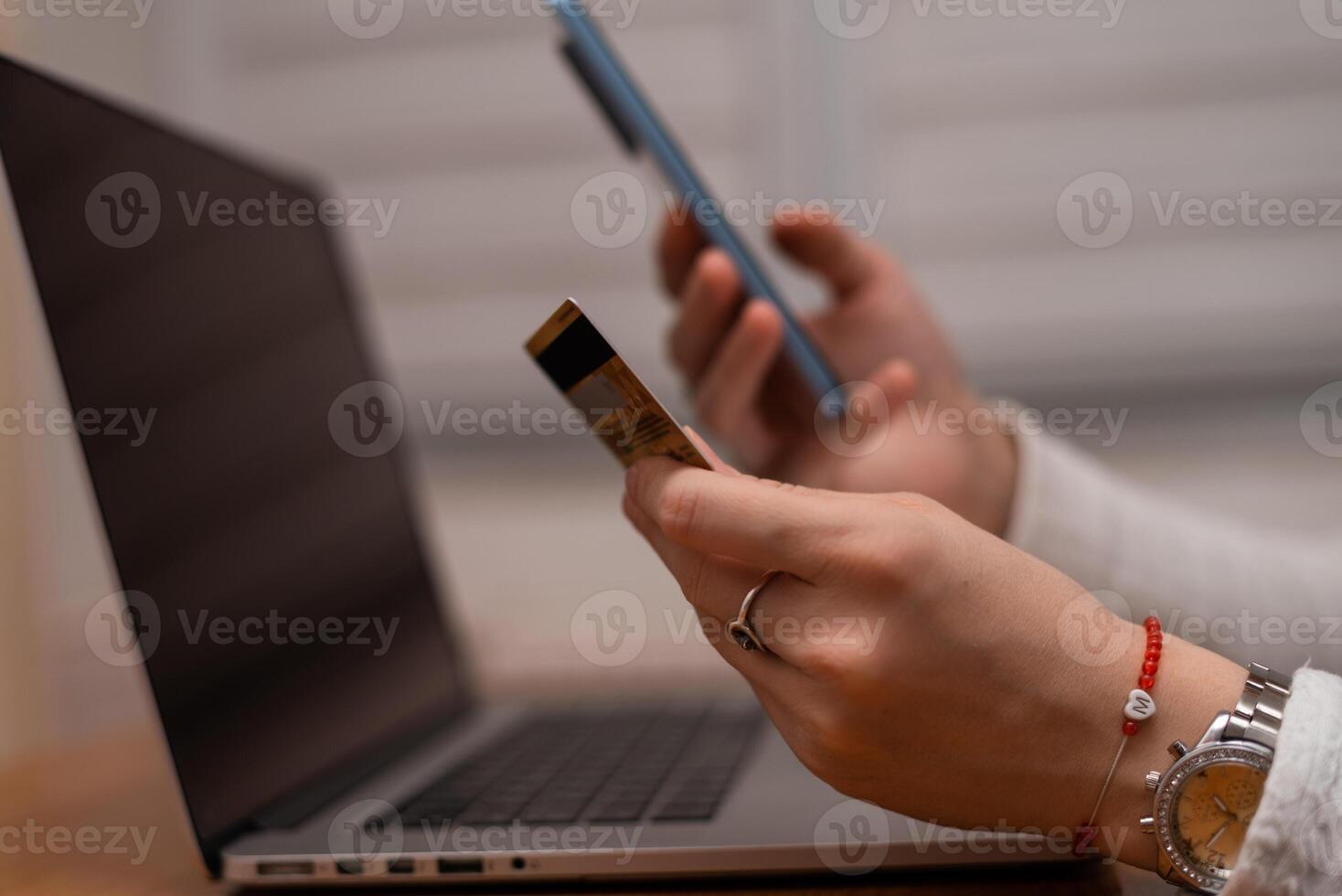 Female hands using mobile phone and holding credit card checking balance or making money transfer. Online Payment Internet Banking Concept. Woman using smartphone for online banking at home close up. photo