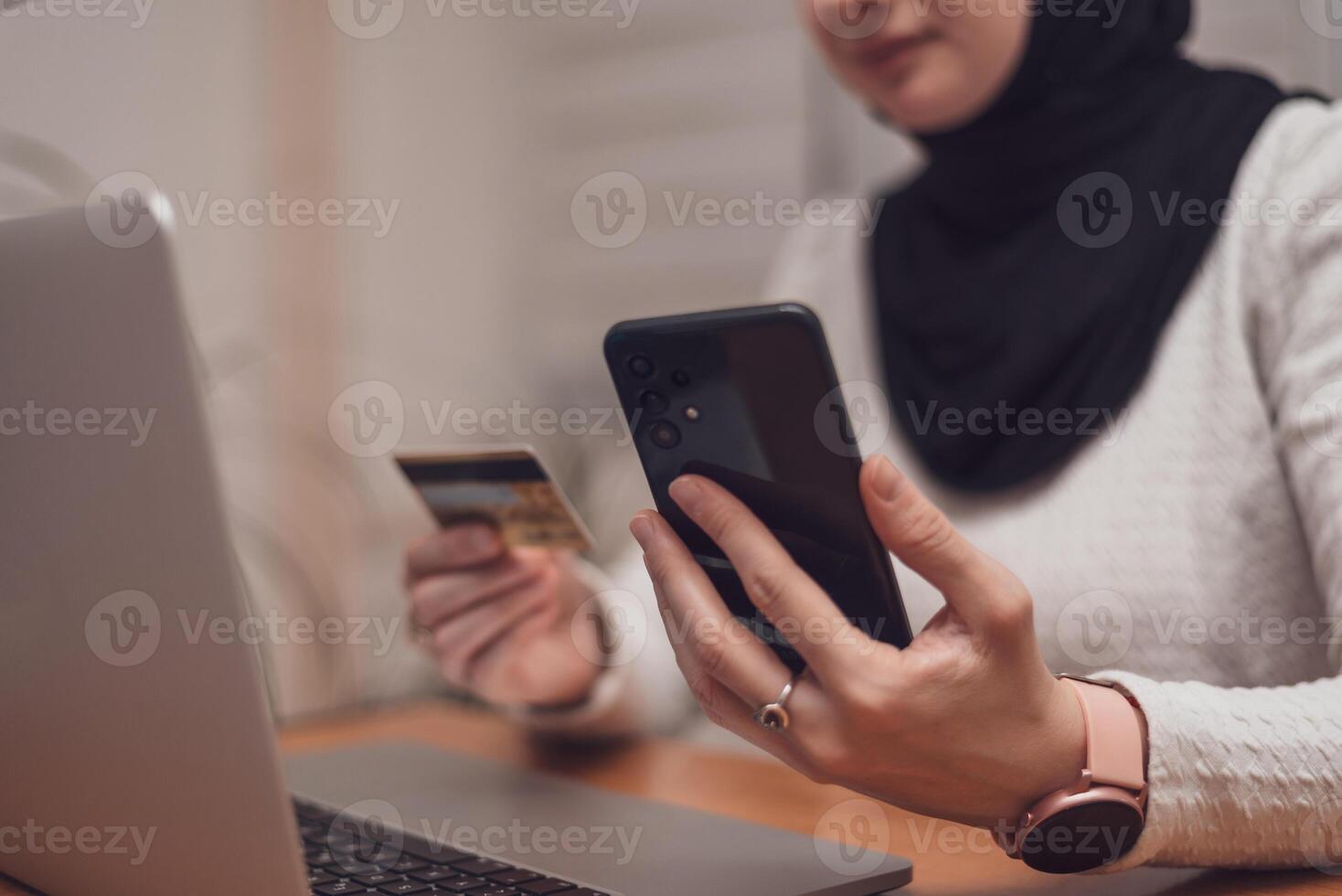 Female hands using mobile phone and holding credit card checking balance or making money transfer. Online Payment Internet Banking Concept. Arabic Woman using smartphone for online banking at home photo