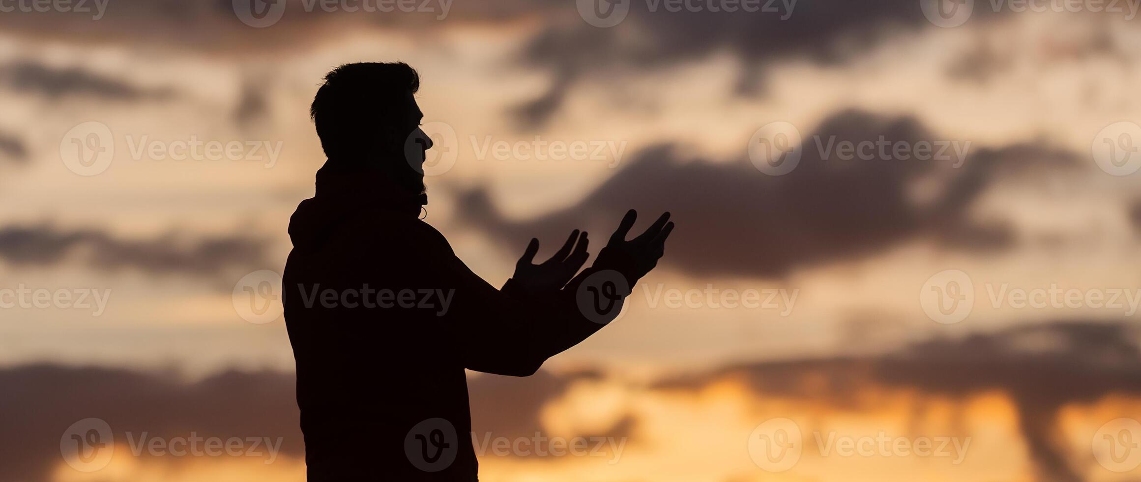 Silhouette of prayer having worship and praying with hands open at sunset photo