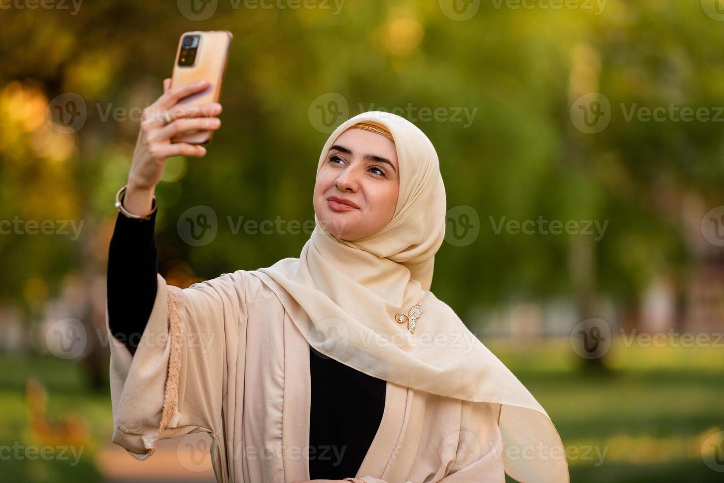 A young happy muslim woman in hijab taking selfie outside. photo