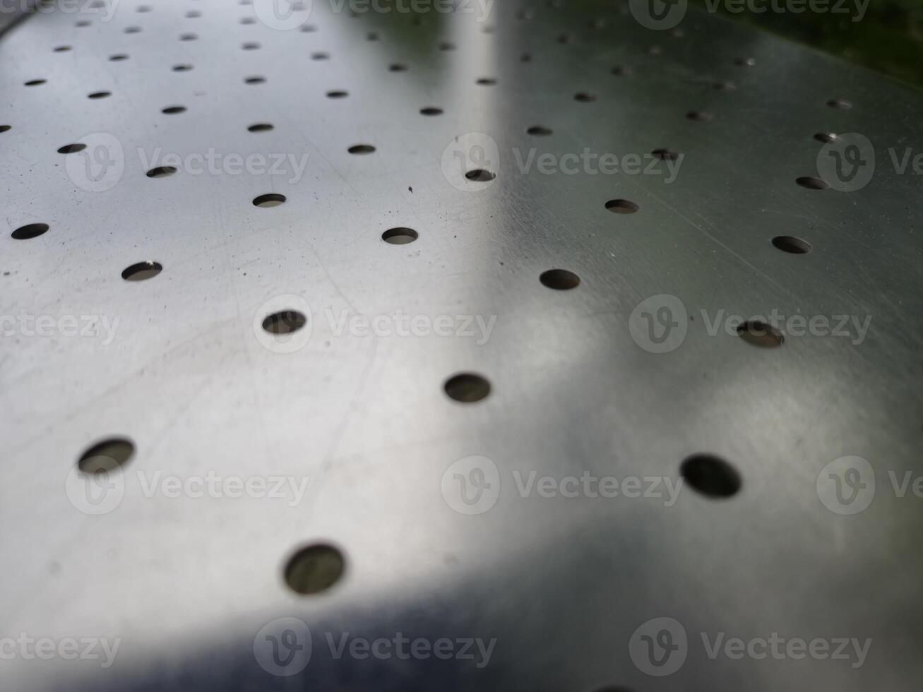 Metal surface with holes abstract background photo