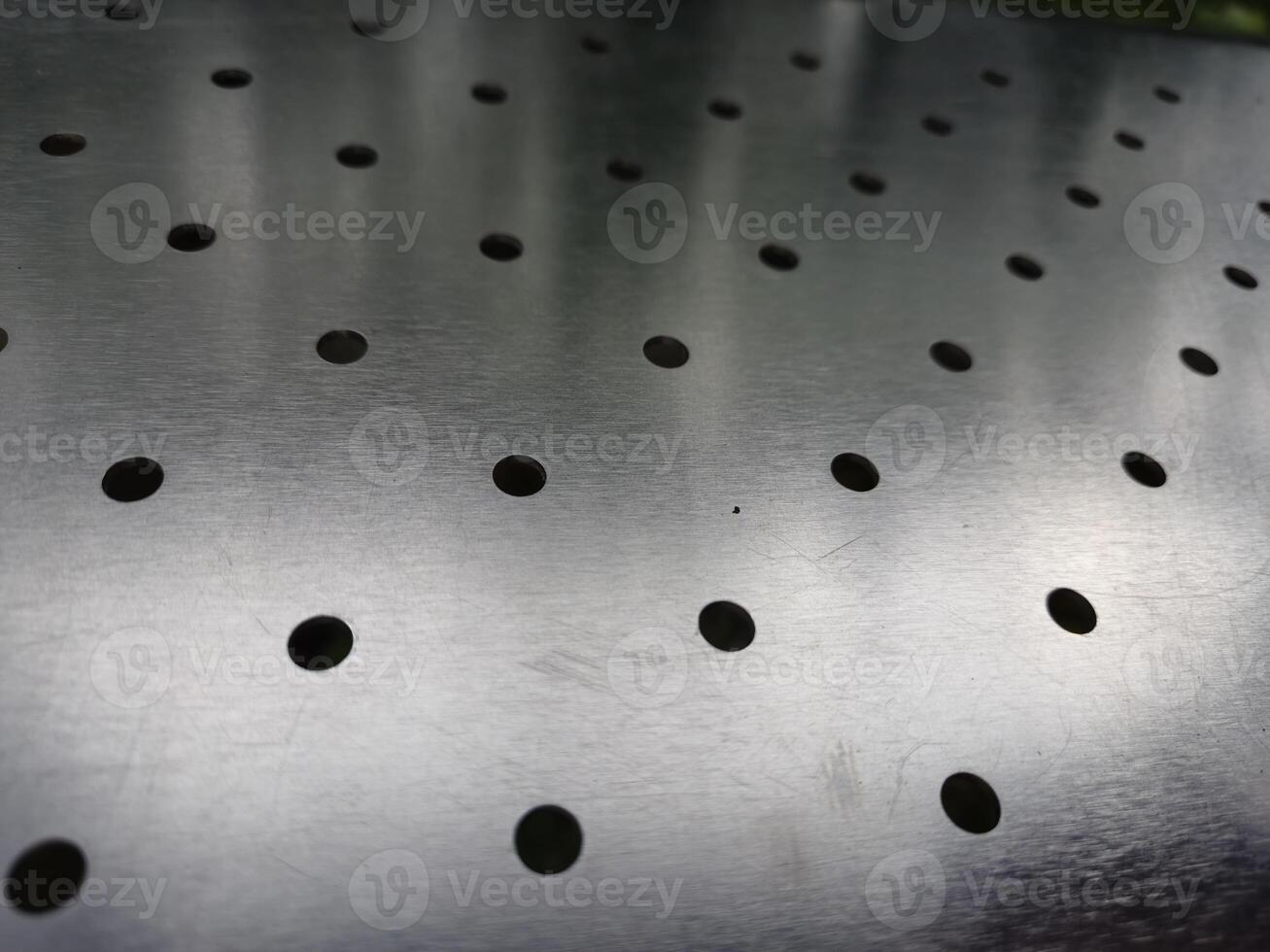 Metal surface with holes abstract background photo