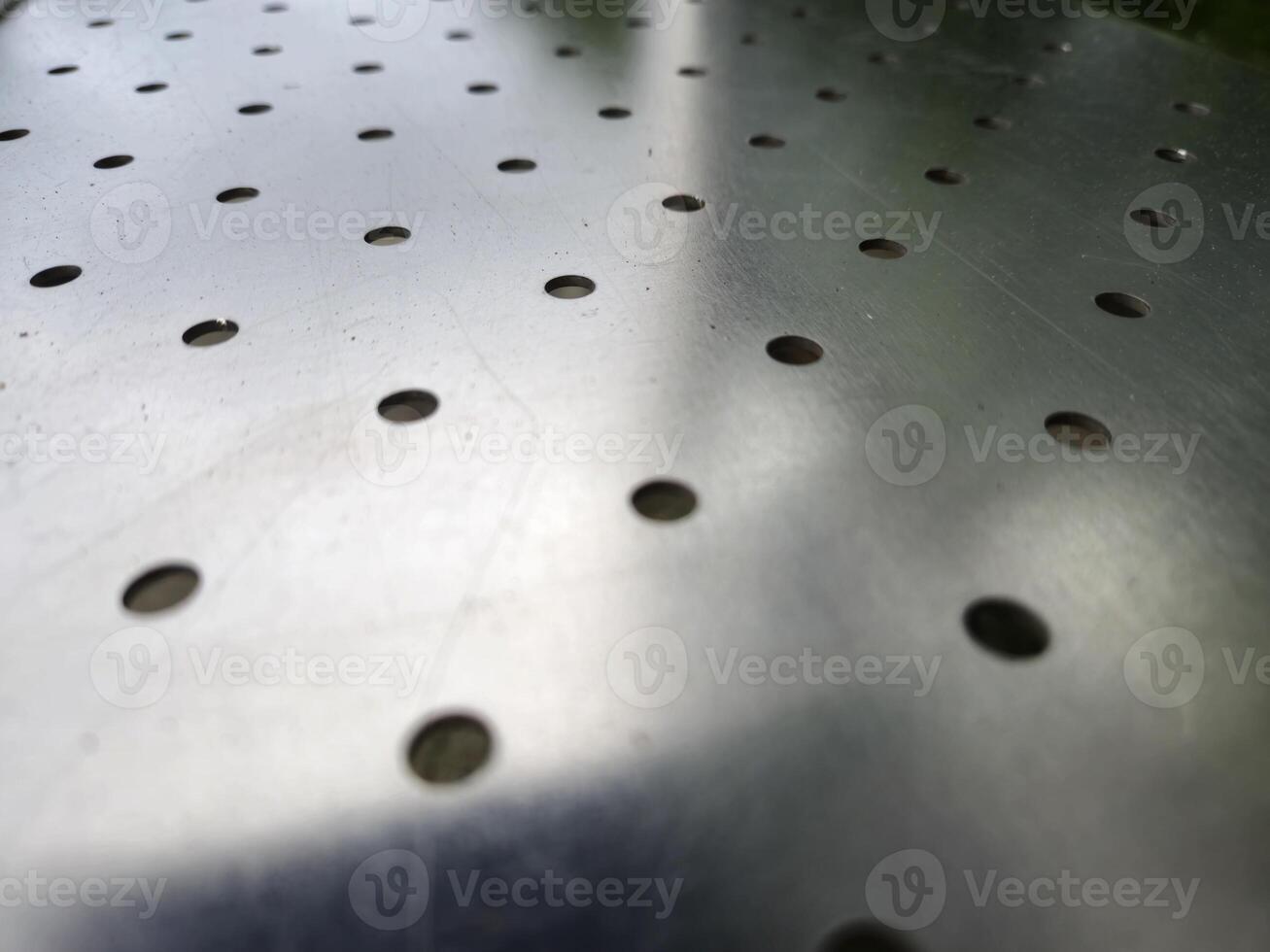 Metal surface with holes abstract background photo