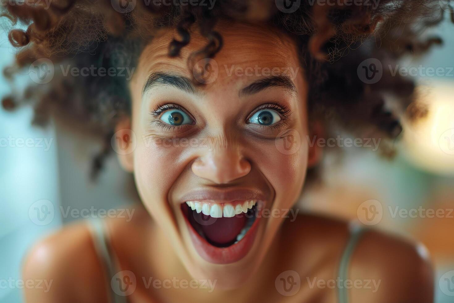 Excited woman with curly hair smiling and laughing photo