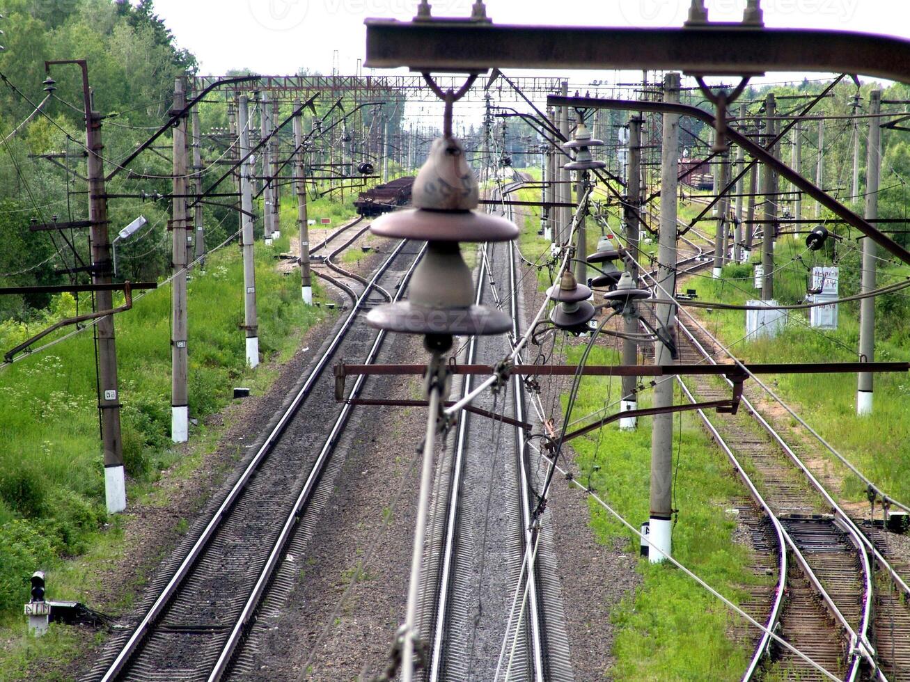 Railway Track with Overhead Power Lines and Vegetation photo