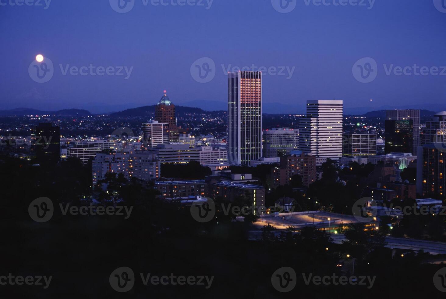 Majestic Skyscraper Under the Dusk Sky with a Glowing Moon on the Horizon photo