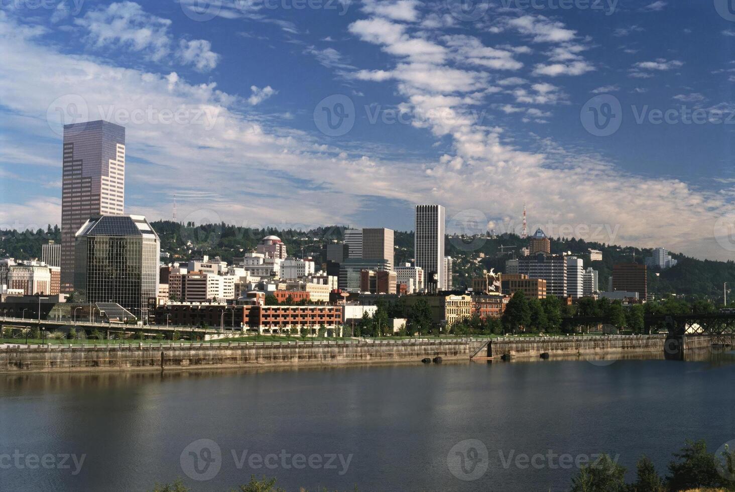 Modern Skyscraper Reflected in Water Under a Blue Sky with Fluffy Clouds photo