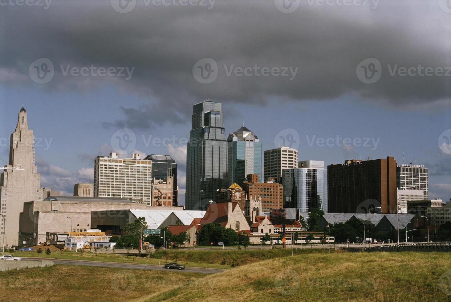 Urban Skyline with Skyscrapers and Greenery Against a Cloudy Sky photo