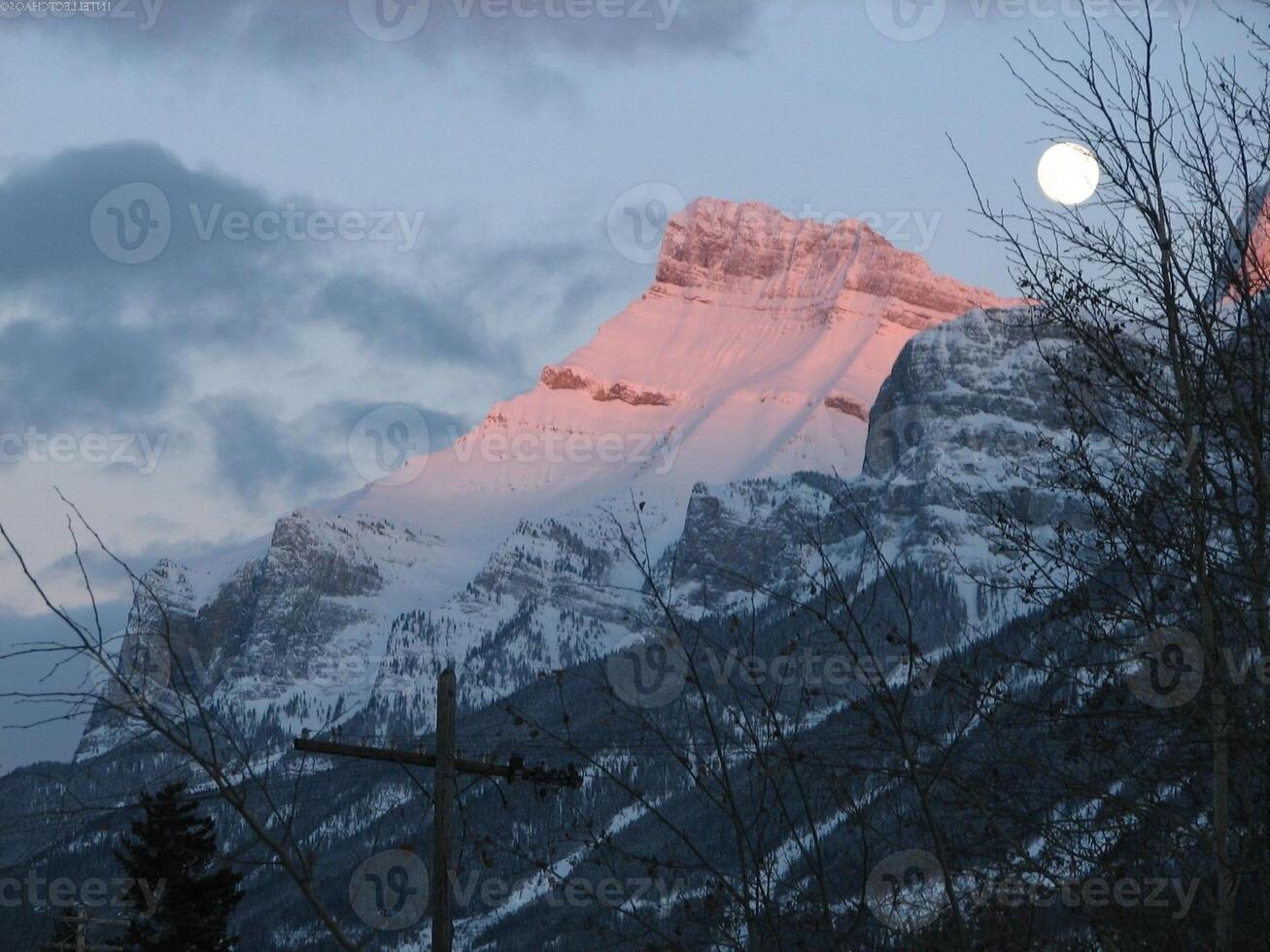 Mountain Landscape with Clouds, Snow, Moon, and Sunlight photo