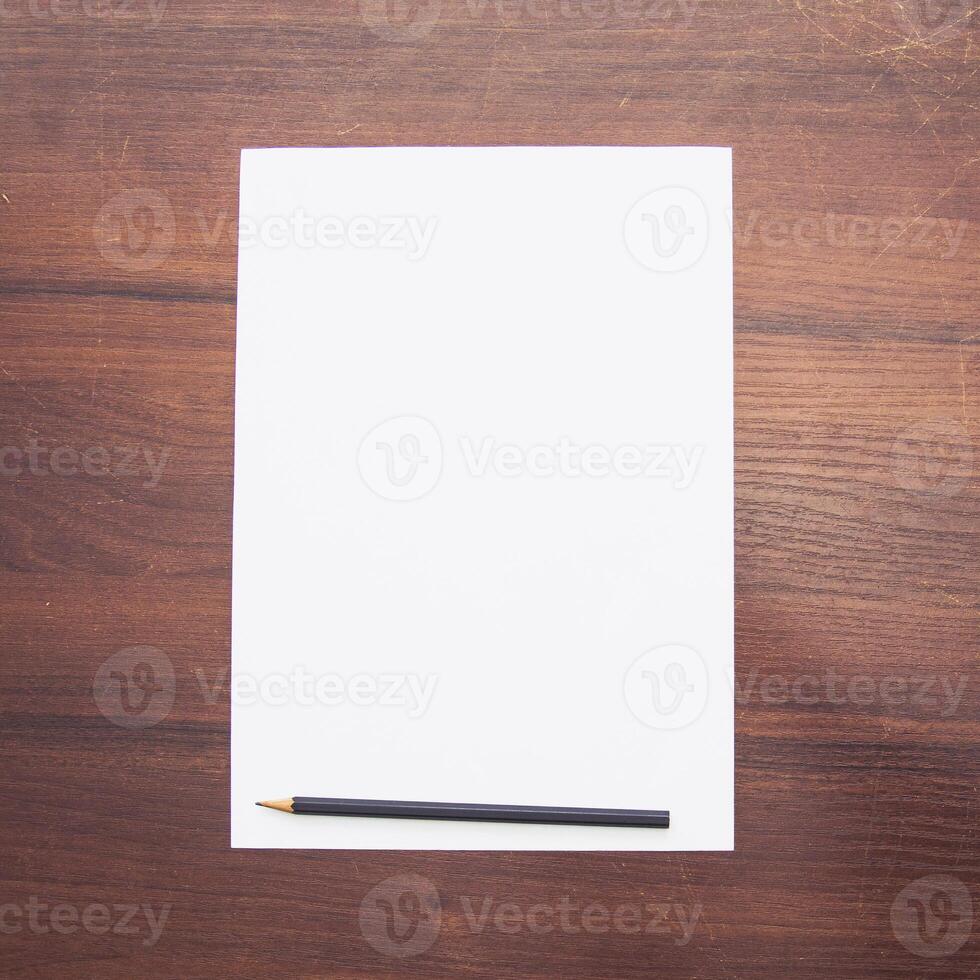 Blank paper on wooden table with pencil photo