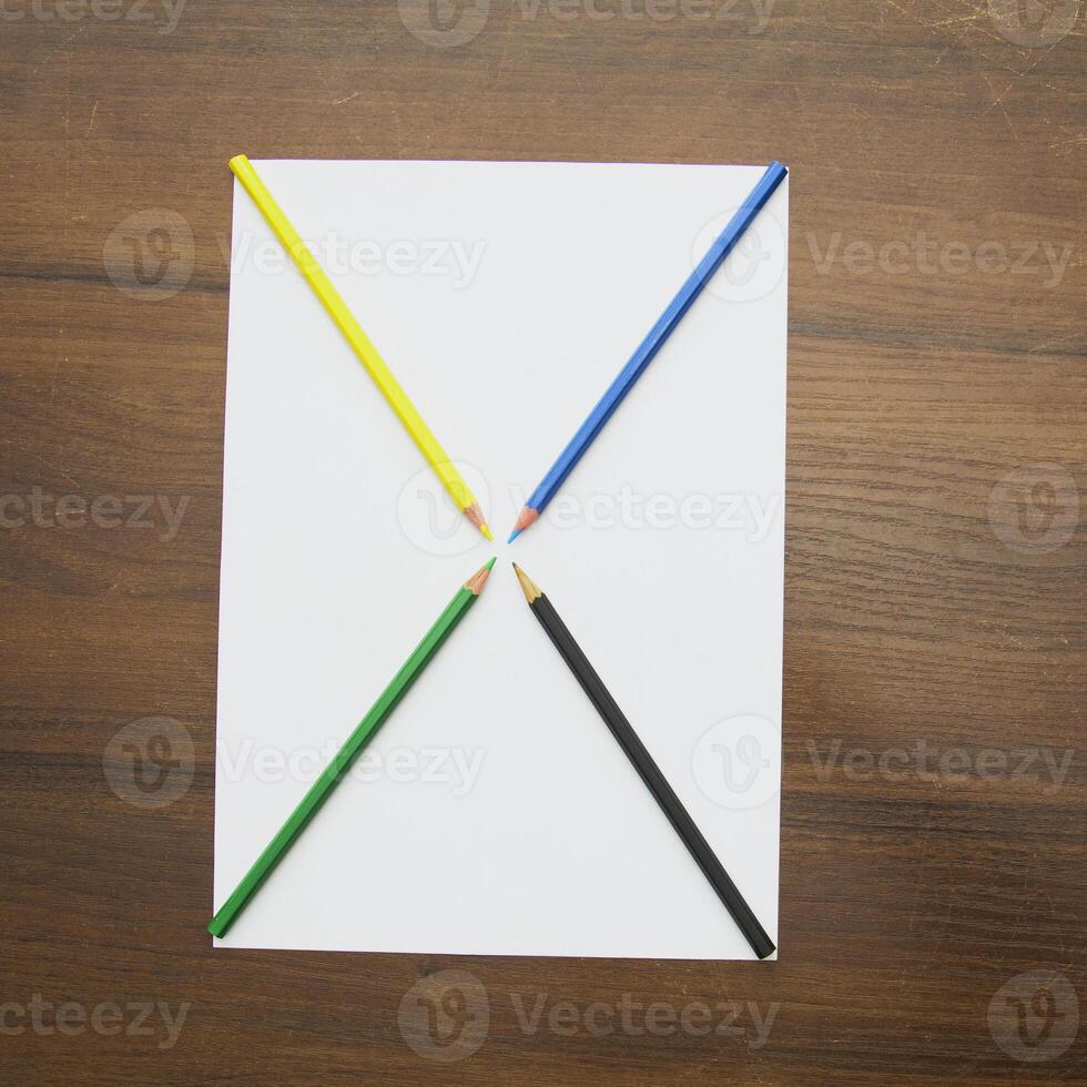 A white sheet with four colored pencils on it photo