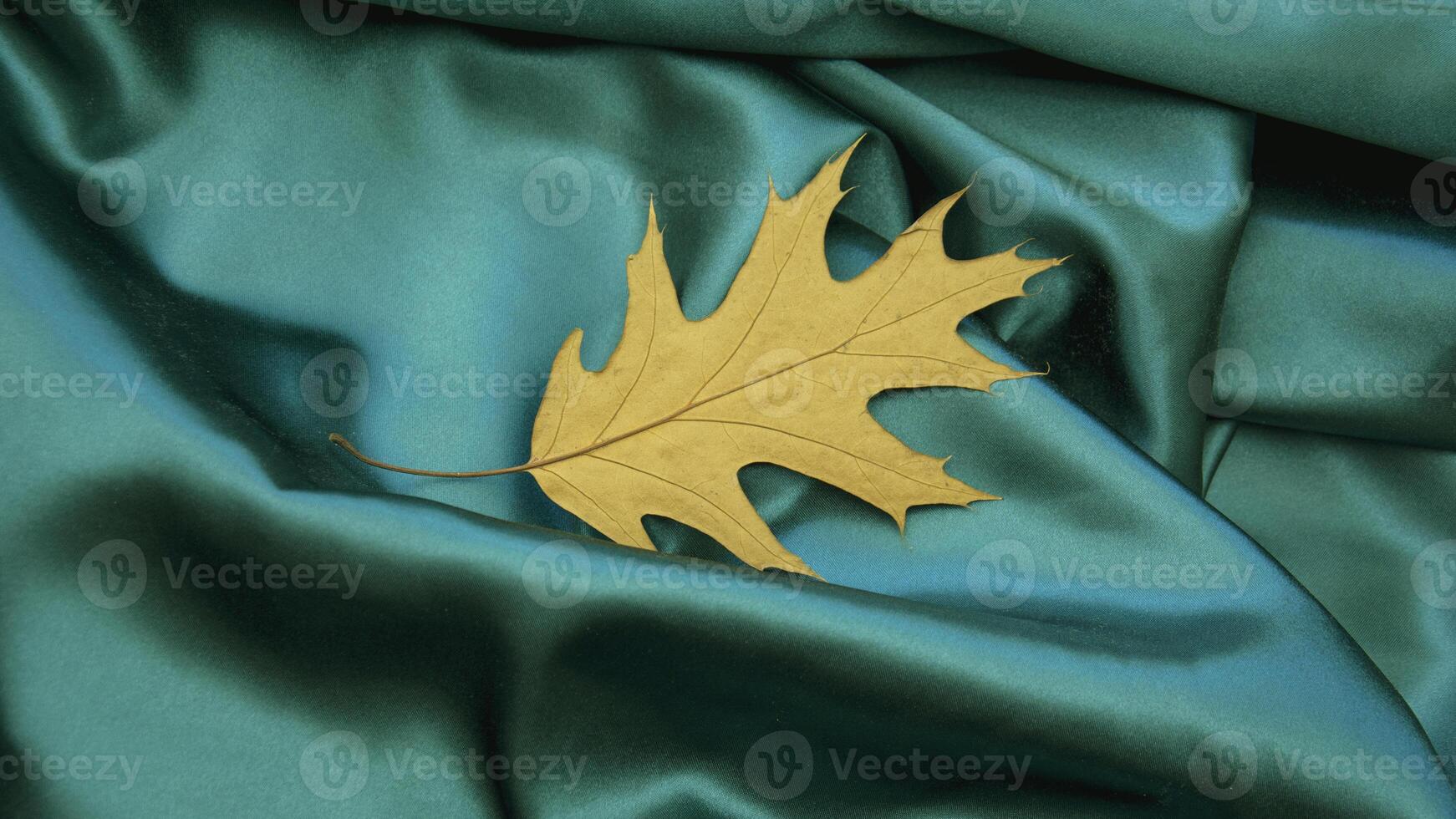 A golden leaf on a blue satin cloth photo